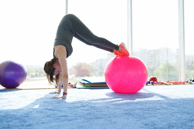 Zdjęcie fitness kobieta. piękne kobiety rasy kaukaskiej robienie ćwiczeń z piłką w siłowni