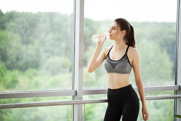 Fitness kobieta pije wodę z butelki po treningu