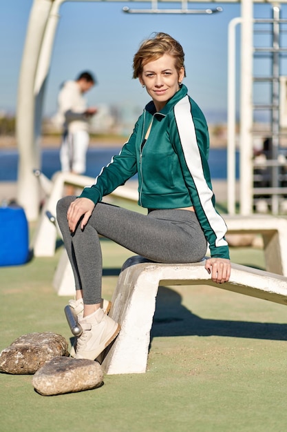 Fitness kobieta robi przysiady w siłowni na świeżym powietrzu, budząc trening siłowy