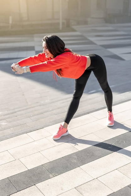 Fitness kobieta rozciąga się i ćwiczy na świeżym powietrzu w środowisku miejskim