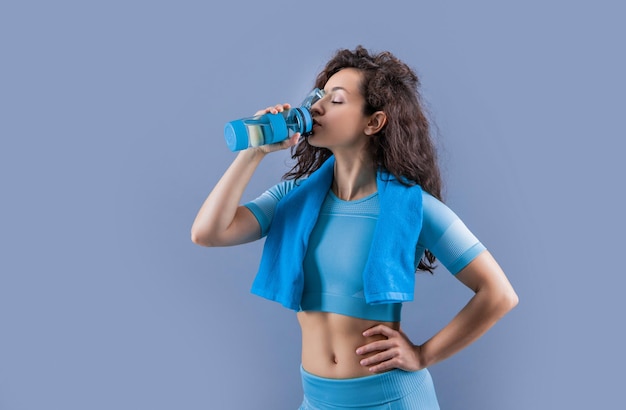 Fitness kobieta z ręcznikiem sportowym pije wodę w studio fitness kobieta trzyma sportowego ręcznika pije wodę