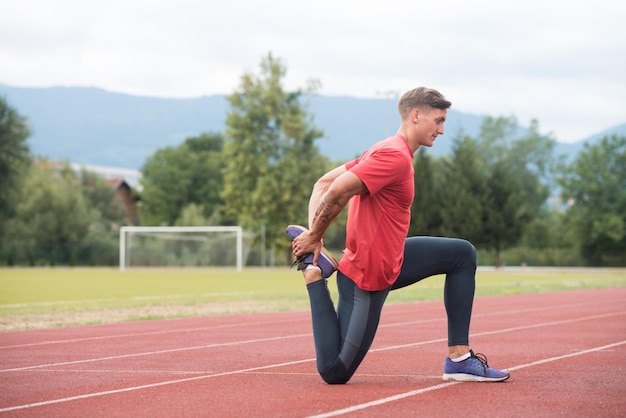 Fitness Man rozciągający się przed treningiem biegającym po torze