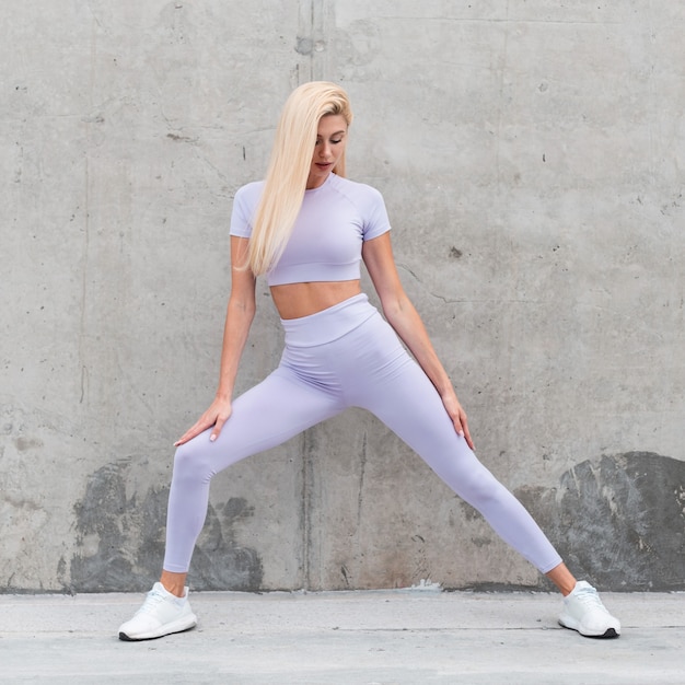 Fitness model dziewczyna w modnej odzieży sportowej robi ćwiczenia na ulicy