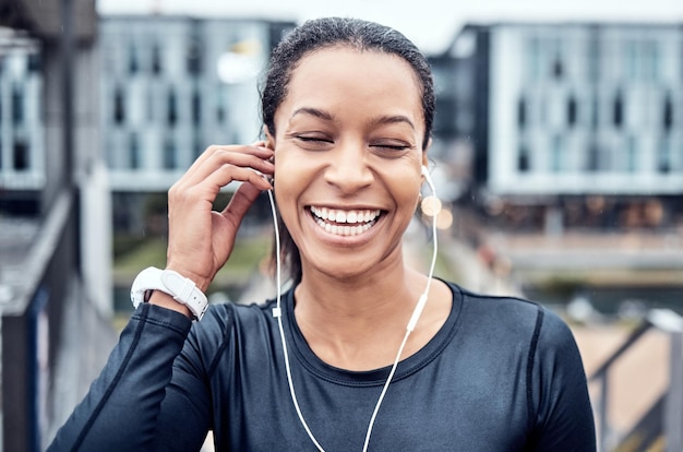 Fitness muzyczny i twarz czarnej kobiety z uśmiechem w mieście dla dobrego samopoczucia zdrowego treningu ciała i cardio Słuchawki sportowe i dziewczyna słuchająca dźwięku do ćwiczeń biegowych i treningu maratońskiego