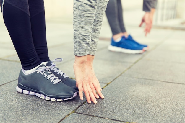 fitness, sport, ćwiczenia, trening i koncepcja ludzi - zbliżenie pary rozciągającej się na ulicy miasta