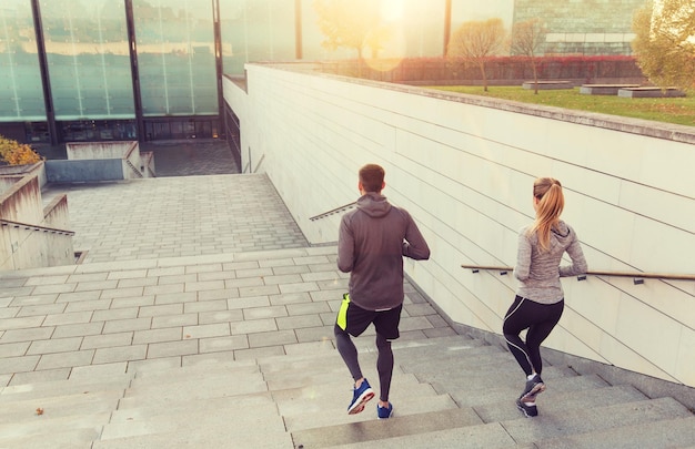 fitness, sport, ludzie, ćwiczenia i koncepcja stylu życia - para biegająca po schodach miejskich