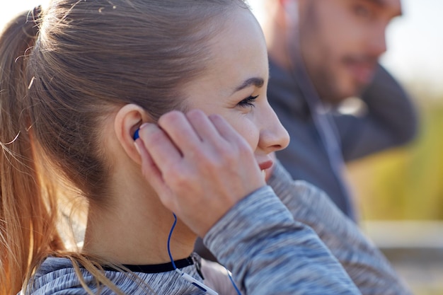 Fitness, Sport, Ludzie, Technologia I Koncepcja Stylu życia - Szczęśliwa Para Na świeżym Powietrzu I Słuchanie Muzyki W Słuchawkach