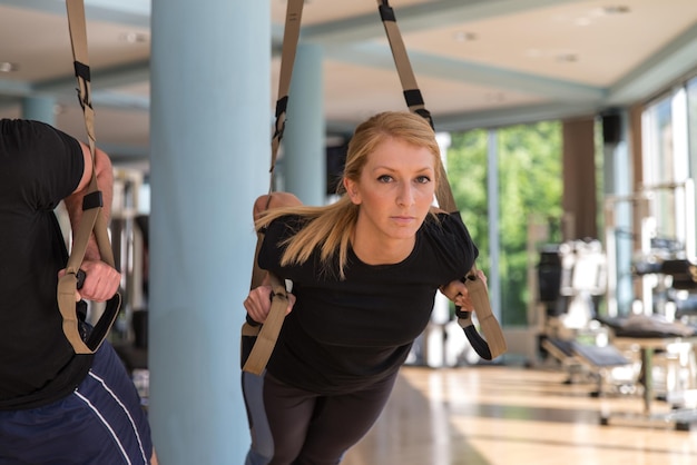 Fitness Trx Zawieszenie Pasy Ćwiczenia treningowe Kobiety i mężczyzna pracujący z własnym Weithem na siłowni