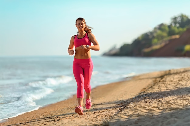 Fitness zawodnik kobieta działa na plaży. Sportowy trening cardio.