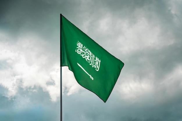 Flaga Arabii Saudyjskiej macha na chmurowym niebie.