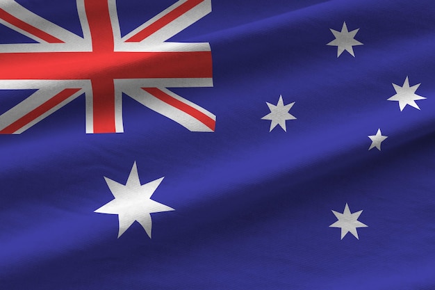 Flaga Australii z dużymi fałdami macha z bliska pod światłem studyjnym w pomieszczeniu Oficjalne symbole i kolory na banerze