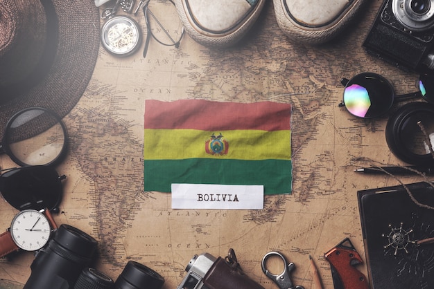 Zdjęcie flaga boliwii między akcesoriami podróżnika na starej mapie vintage. strzał z góry