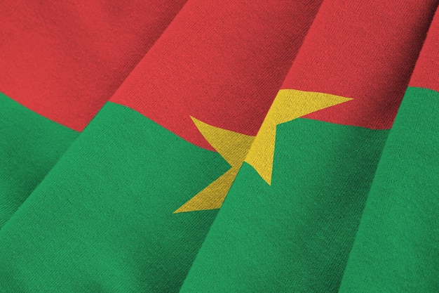 Flaga Burkina Faso z dużymi fałdami macha z bliska pod światłem studyjnym w pomieszczeniu Oficjalne symbole i kolory na banerze