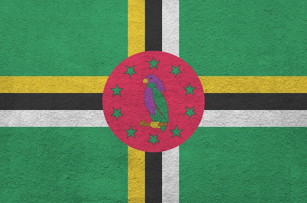 Flaga Dominiki przedstawiona w jasnych kolorach farby na starej reliefowej ścianie tynkarskiej. Teksturowane transparent na szorstkim tle