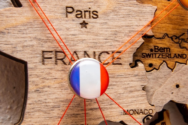Flaga Francji na szpilce z czerwoną nicią pokazała ścieżki na drewnianej mapie