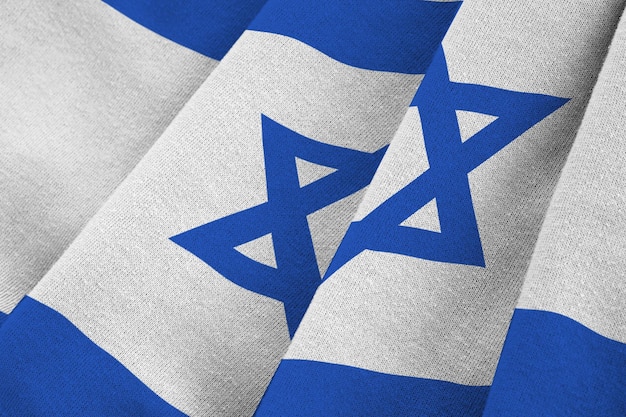 Flaga Izraela z dużymi fałdami macha z bliska pod światłem studyjnym w pomieszczeniu Oficjalne symbole i kolory na banerze