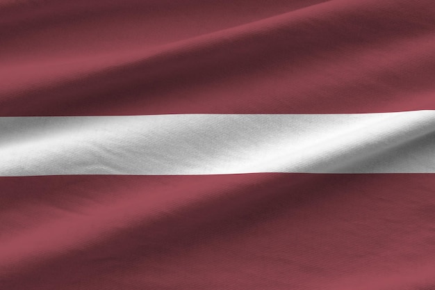 Flaga Łotwy z dużymi fałdami macha z bliska pod światłem studyjnym w pomieszczeniu Oficjalne symbole i kolory na banerze