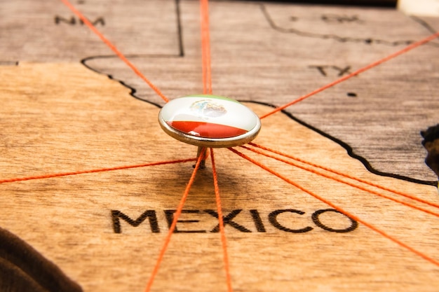 Flaga meksyku na pinezce i czerwonych nitkach na drewnianej mapie