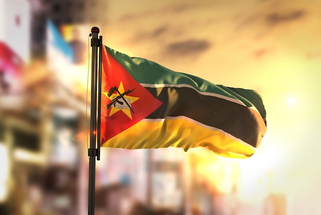 Flaga Mozambiku przeciwko Miastu Rozmyte Tło W Sunrise Backlight