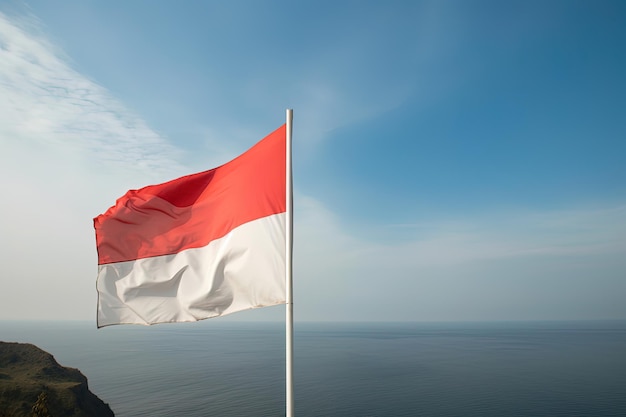 Flaga narodowa Indonezji machająca na błękitnym niebie na tle oceanu Czerwona i biała flaga