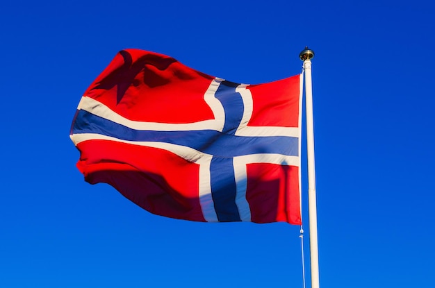 Flaga Norwegii na tle błękitnego nieba, narodowe patriotyczne tło