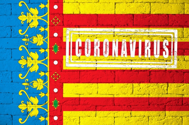 Flaga regionów lub społeczności Hiszpanii Walencja o oryginalnych proporcjach. opieczętowane koronawirusem. cegła ściana tekstur. Koncepcja wirusa koronowego. Na skraju pandemii COVID-19 lub 2019-nCoV.