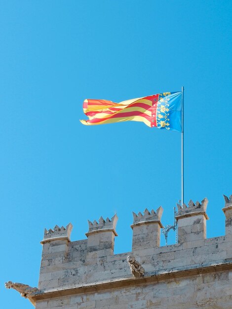 Flaga społeczności Walencji macha na wietrze na tle żywego błękitnego nieba Walencja Hiszpania
