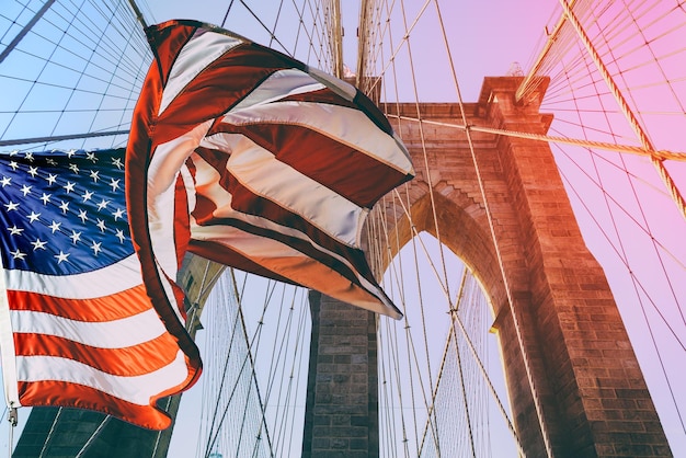 Flaga Stanów Zjednoczonych na szczycie mostu brooklyńskiego jest ciemnoniebieskie niebo na tle na pierwszym planie th