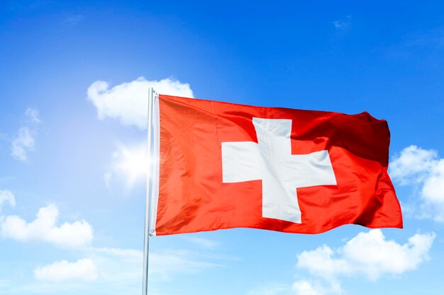 Flaga Szwajcarii wieje na wietrze pod błękitnym niebem