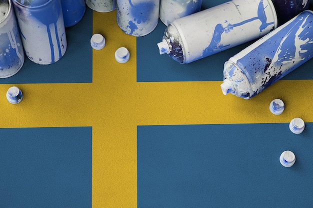 Flaga Szwecji i kilka używanych puszek z aerozolem do malowania graffiti Koncepcja kultury sztuki ulicznej