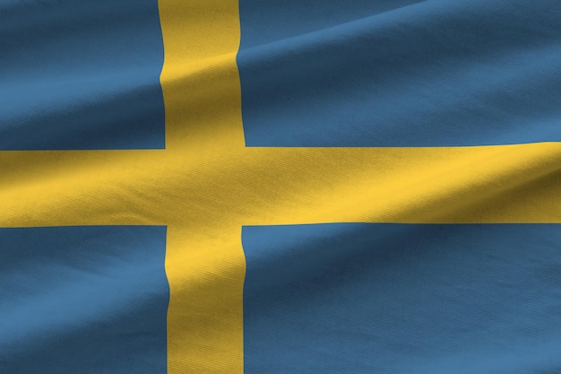 Flaga Szwecji z dużymi fałdami machającymi z bliska pod światłem studyjnym w pomieszczeniu Oficjalne symbole i kolory na banerze