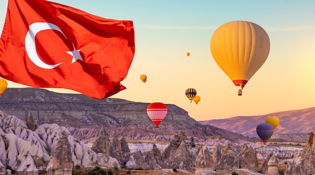 Zdjęcie flaga turcji przeciwko balonom na ogrzane powietrze w zachodzie słońca na niebie unoszącym się nad górami