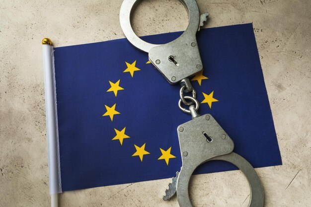 Flaga UE i kajdanki na abstrakcyjnym tle, pojęcie przestępczości w społeczeństwie europejskim