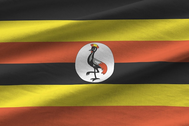 Flaga Ugandy z dużymi fałdami machającymi z bliska pod światłem studyjnym w pomieszczeniu oficjalne symbole i ok