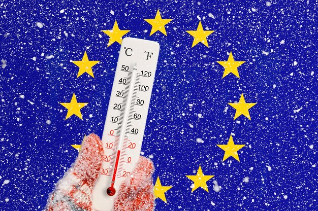 Zdjęcie flaga unii europejskiej i opady śniegu termometr w skali celsjusza i fahrenheita w ręku