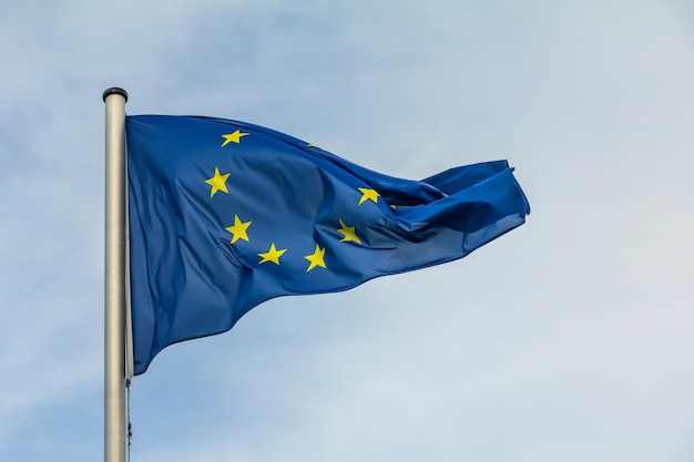 Flaga Unii Europejskiej macha na niebieskim tle