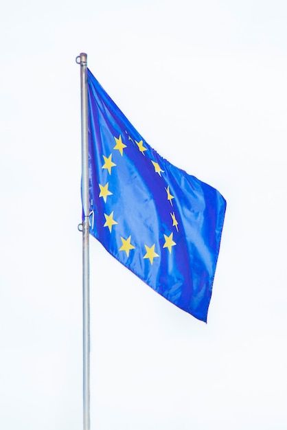 Flaga unii europejskiej rozwija się na wietrze na zbliżeniu masztu na białym tle na białym tle