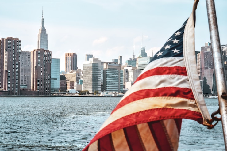 Zdjęcie flaga usa na pierwszym planie oraz budynki biurowe i apartamenty na panoramie o zachodzie słońca. koncepcja nieruchomości i podróży. manhattan, nowy jork, usa.
