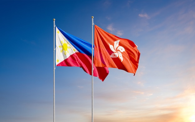 Flagi Filipin i Hongkongu powiewają razem na wietrze na niebie o wschodzie słońca