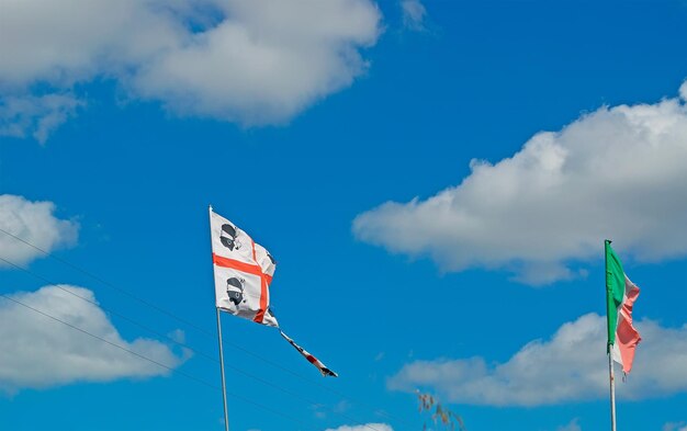 Flagi Sardynii i Włoch pod błękitnym niebem