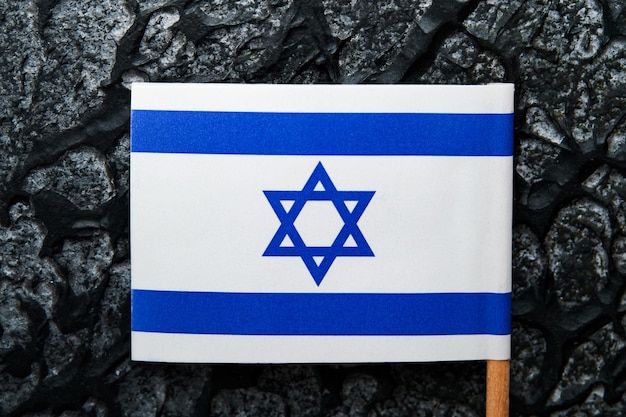 Flagi USA i Izraela Dwie małe flagi amerykańskiej i izraelskiej leżą na czarnym, starym tle tekstury naprzeciw siebie, przekazując partnerstwo między dwoma państwami poprzez główne symbole tych krajów Makieta