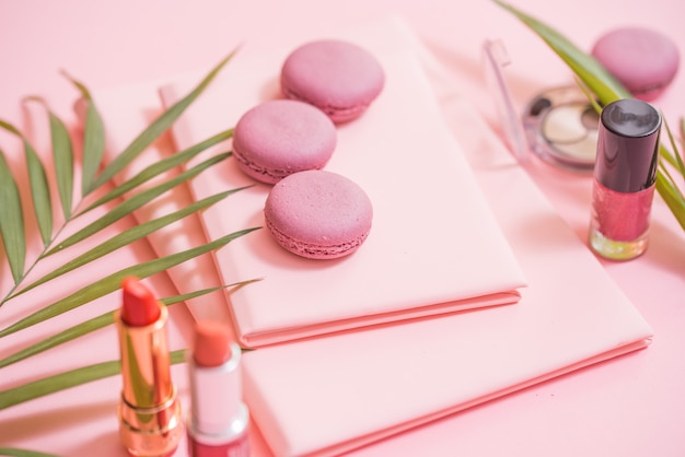 Flatlay notebooka, ciasto macaron, kwiat na różowym stole. Piękne śniadanie z makaronikiem