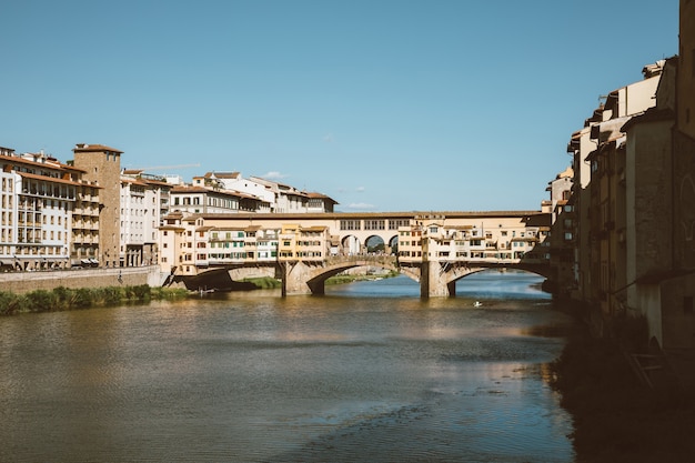 Florencja, Włochy - 26 czerwca 2018 r.: Panoramiczny widok na Ponte Vecchio (stary most) to średniowieczny kamienny most łukowy segmentowy zamknięty spandrel nad rzeką Arno we Florencji. Letni dzień i błękitne niebo