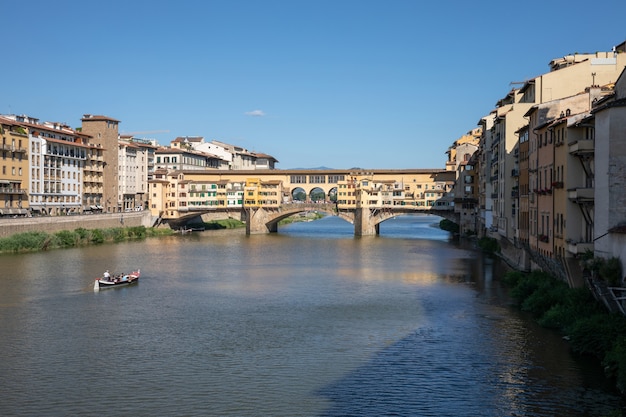 Florencja, Włochy - 26 czerwca 2018 r.: Panoramiczny widok na Ponte Vecchio (stary most) to średniowieczny kamienny most łukowy segmentowy zamknięty spandrel nad rzeką Arno we Florencji. Letni dzień i błękitne niebo