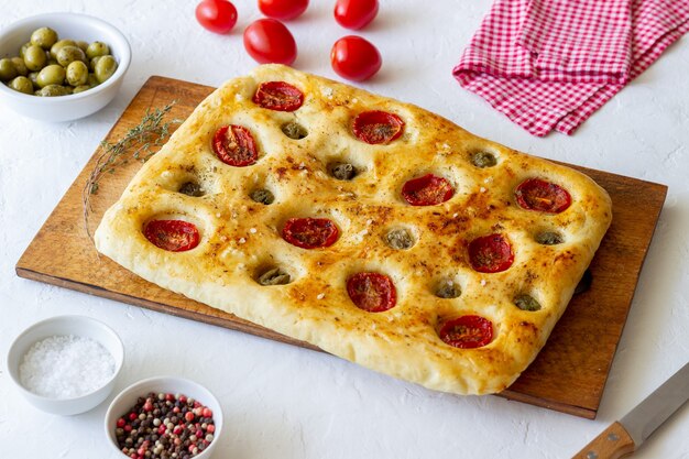 Focaccia z pomidorami i oliwkami. Jedzenie wegetariańskie. Włoskie jedzenie.