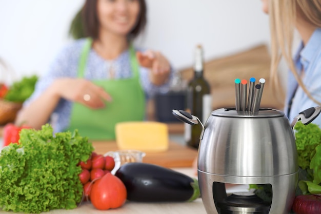 Fondue w garnku na tle przyjaciół gotujących razem zbliżenie Wnętrza kuchni i naczynia