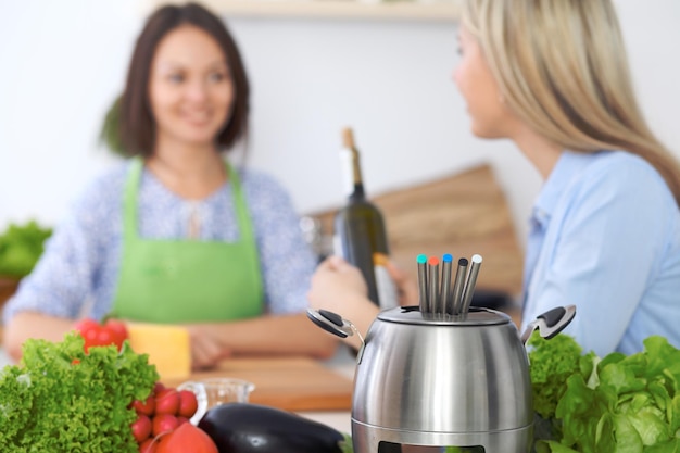 Fondue w garnku na tle przyjaciół gotujących razem zbliżenie Wnętrza kuchni i naczynia