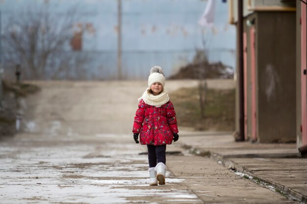 Fool-dług Portret ładny Mały Młody śmieszne Dziecko ładne Dziewczyny W ładne Ciepłe Zimowe Ubrania Chodzenie Pewnie Samotnie Na Białym Jasnym Na Zewnątrz Niewyraźne Kopia Tło. Zajęcia Na świeżym Powietrzu.