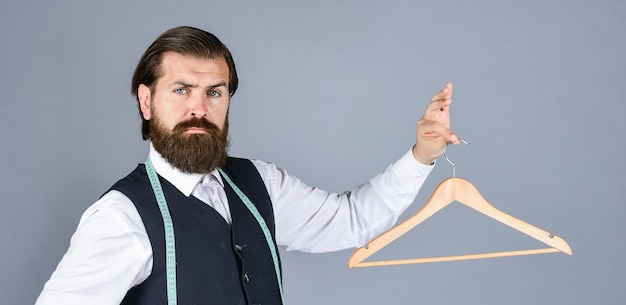 Zdjęcie formalna stylowa odzież męska na wieszaku stojak w pokoju krawiec mężczyzna trzyma w ręku wieszak przystojny mężczyzna w formalnej kamizelce szafa dla biznesu moda odzież i zakupy