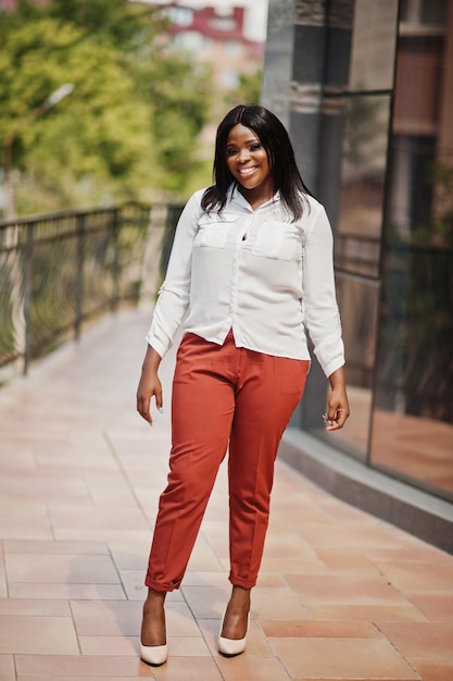 Formalnie ubrana afroamerykańska kobieta biznesu w białej bluzce i czerwonych spodniach Udana ciemnoskóra bizneswoman